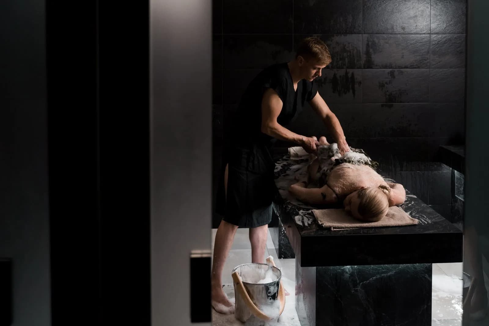 Soapy foam massage during a traditional hammam ritual in a marble bath