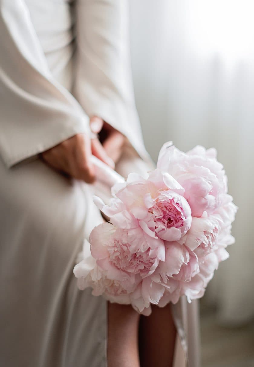 Hands in a white spa robe holding a peony — a personalised gift voucher
