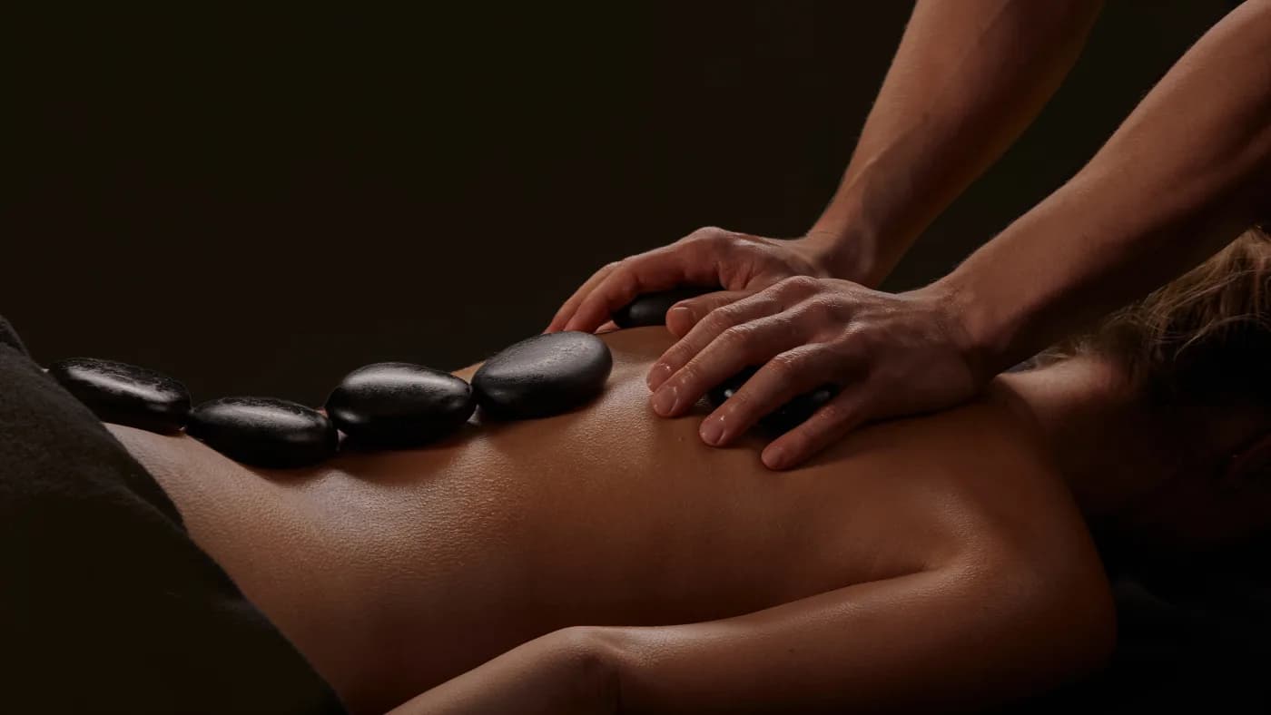 American hot stone massage in Malta — heated basalt stones for deep muscle relief at Carisma Spa