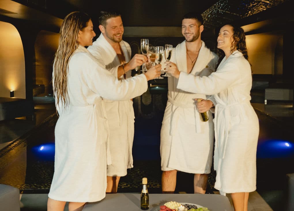 Friends in spa robes toasting with champagne at Carisma Spa